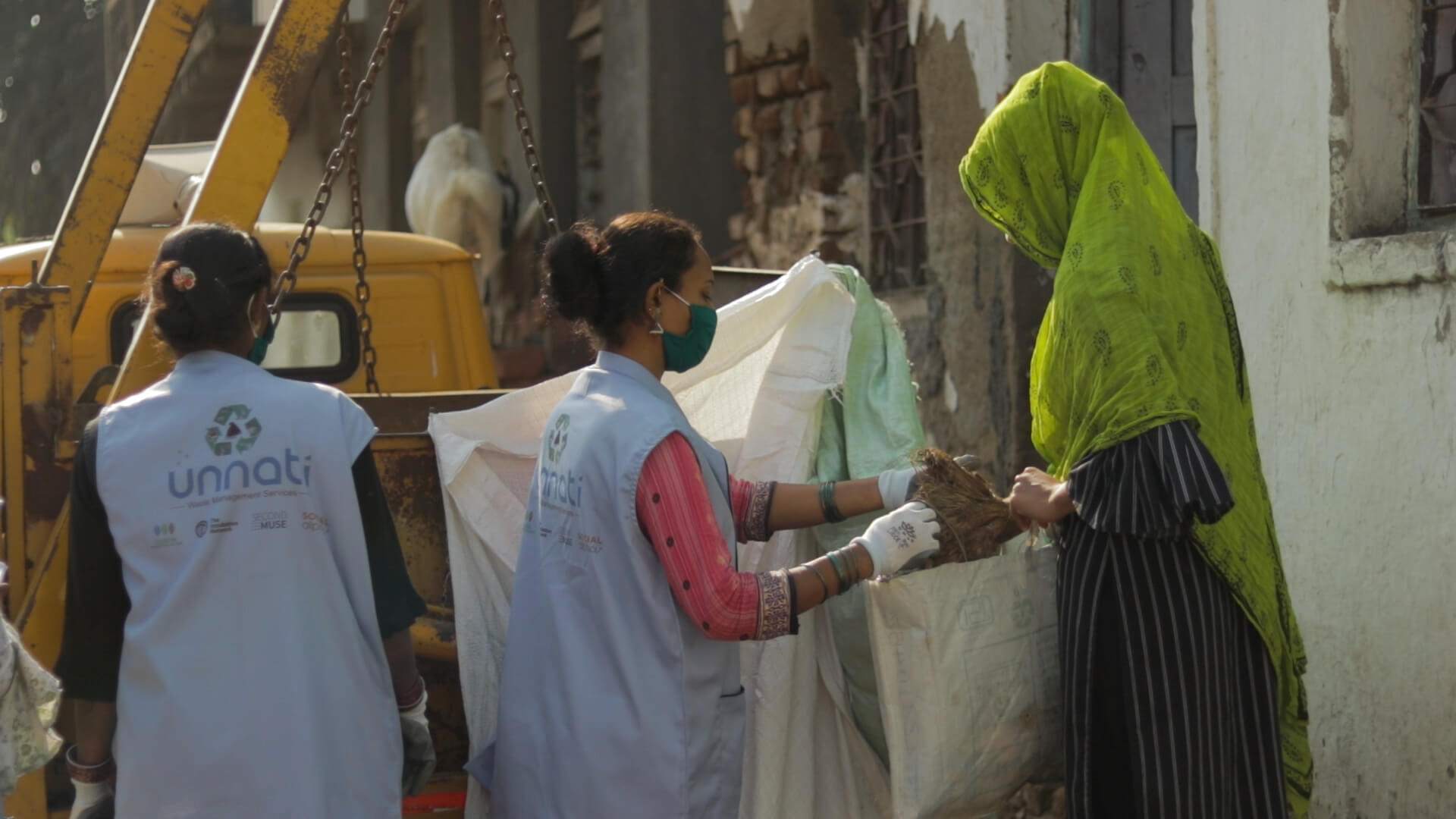 Two Unnati members collecting waste from a resident